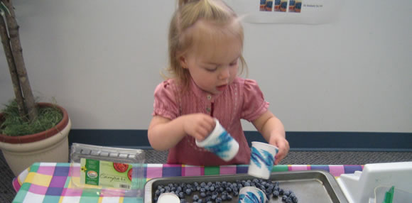Picture of girl playing with cups and beads and link to Homepage